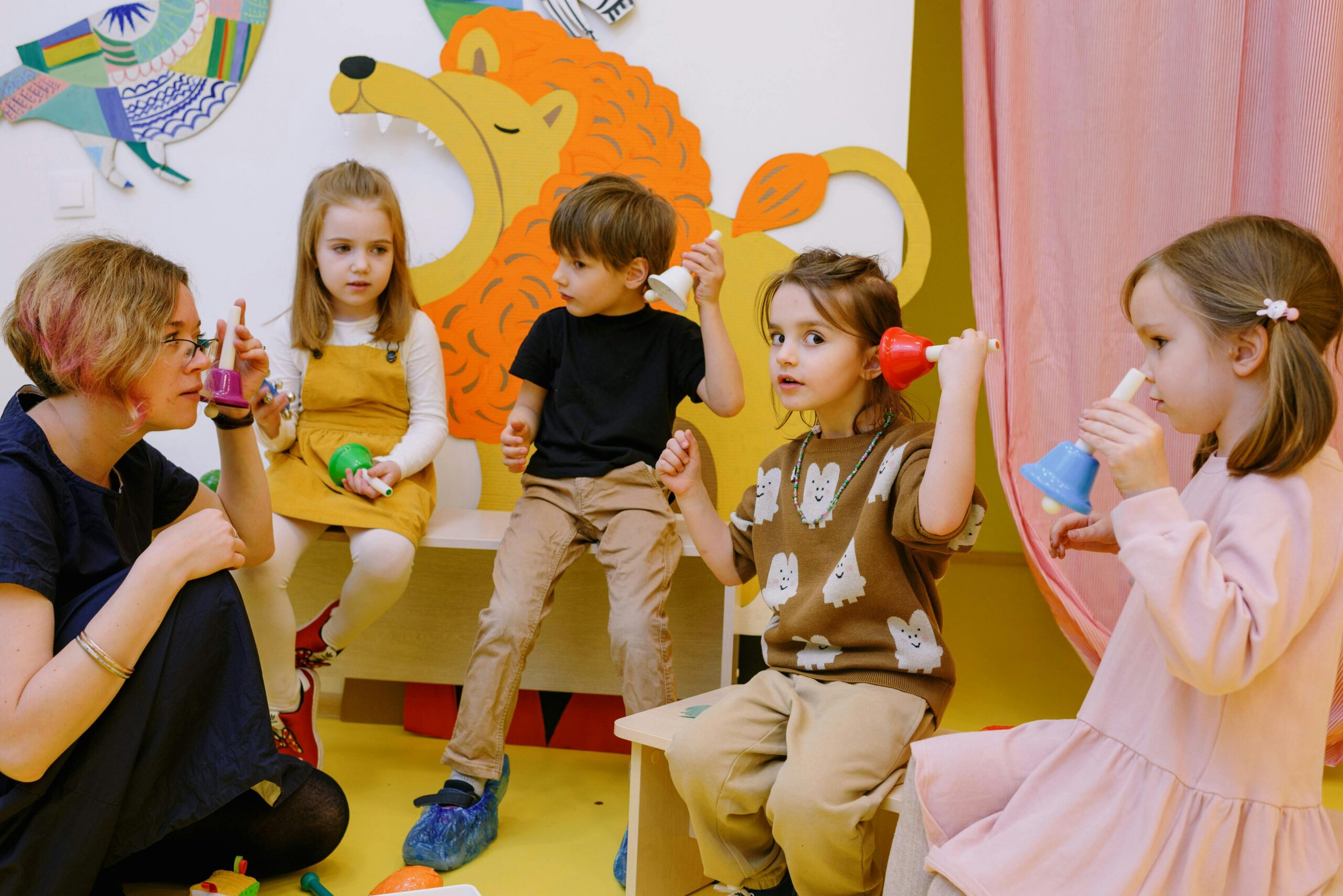 Children engaging in playful music activities with colorful bells in a vibrant classroom setting, highlighting Smartyca's enriching summer camp programs for kids.